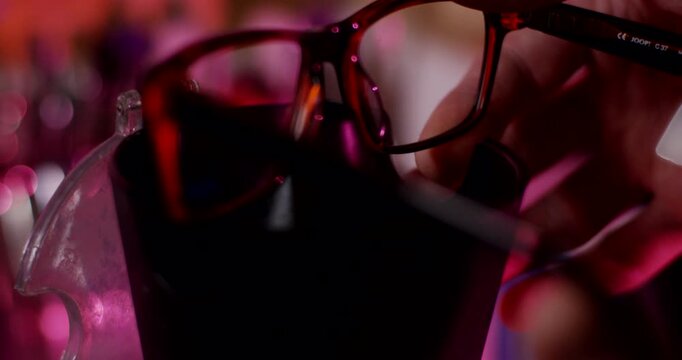 Close up of technician hand holding eyeglasses during professional inspection in optical laboratory