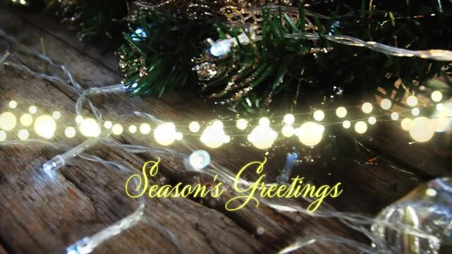 Animation of text, season's greetings, in yellow, over string lights and christmas tree decorations