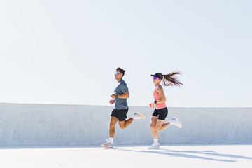 Couples running joyfully under a bright blue sky in a sunny urban setting during late morning hours