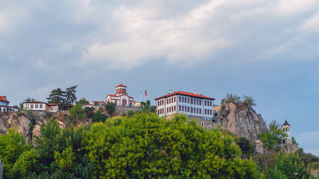 Plovdiv old town with historic houses and church complex on rocky hill surrounded by trees. Architecture and cityscape in Plovdiv Bulgaria. Concept of heritage tourism, culture travel