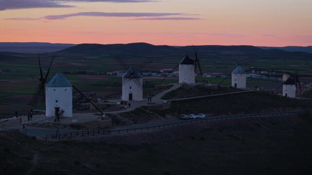 Famous historic windmills of Consuegra in Castilla La Mancha, Spain, dotting the rural landscape during a beautiful and colorful sunset with dramatic light