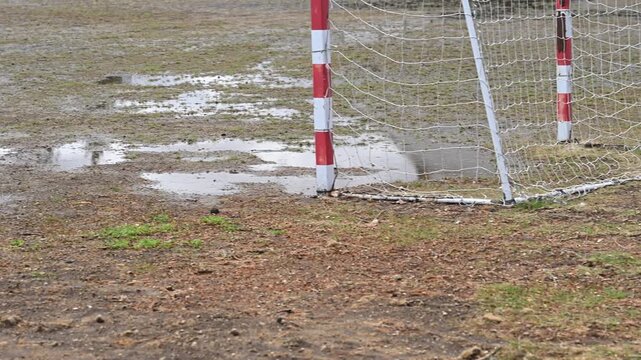 閉校となった小学校の荒れた校庭。雨上がりのグランドの水たまりと残されたサッカーゴール。冬の風景。