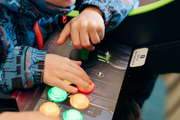 Close up of child hands playing arcade game with colorful buttons and joystick © Sergei