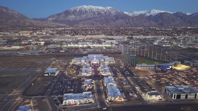 Drone shot of the Megaplex theater and Top Golf in Vineyard Utah during twilight with snowcapped mountains in the background
