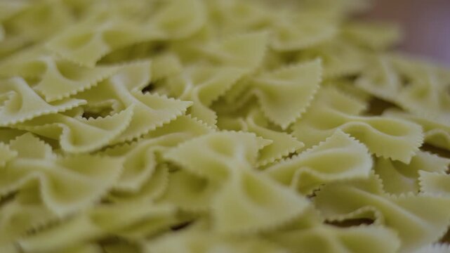 Uncooked Bow Tie Pasta On Table Dry, A vibrant video of dry bow tie pasta on a table, capturing natural and culinary simplicity, perfect for food documentary and culinary.