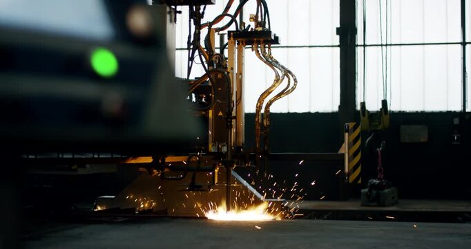 Automated CNC gas cutting machine processing metal with bright sparks in a factory workshop