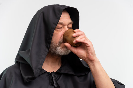 Bearded monk with hood drinking beverage on white background isolated