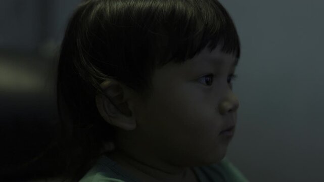 Close Up Toddler Watching TV, A candid documentary clip of toddler dashing along dam path, wind in hair under blue sky, ideal for family outing film or pure freedom documentary.