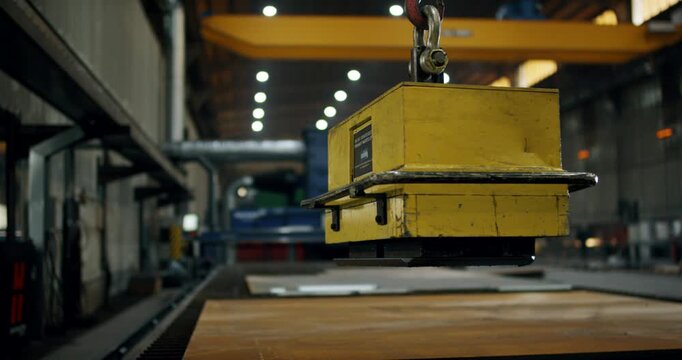 Close up of industrial magnetic lifter carrying a metal plate in a factory workshop