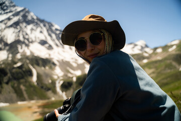 Fototapeta premium Happy woman hiker resting in the mountains, looking at the camera and enjoying summer trekking.