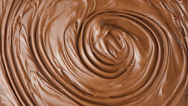 Macro texture of glossy chocolate nut cream swirling patterns