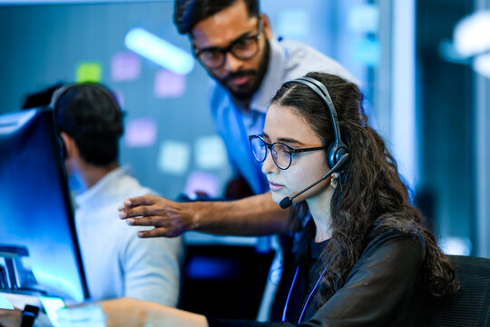 Call center quality assurance supervisor monitoring agent performance protocols. Corporate trainer mentoring workforce on operational compliance.