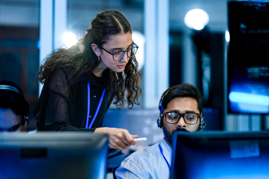 IT service management specialist resolving technical support tickets with supervisor. Female operations manager auditing workstation workflow efficiency strategies.