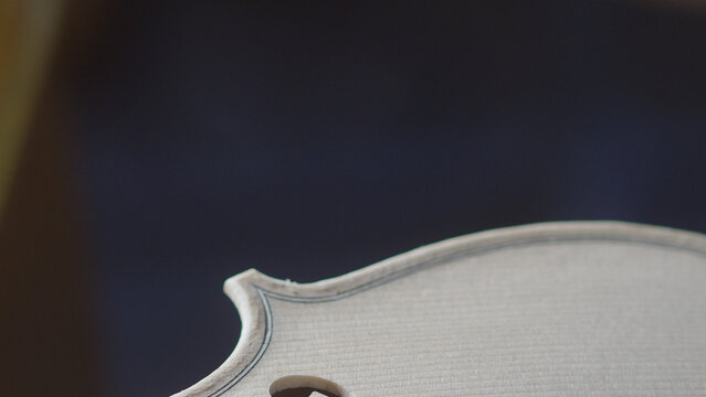 Close-up of a newly crafted white violin body revealing intricate details of its construction and the delicate grain of the wood perfect for showcasing craftsmanship and musical artistry in