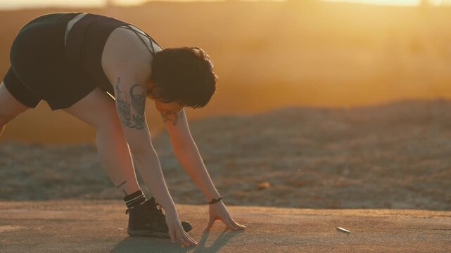 Tattooed woman stretching legs at sunset