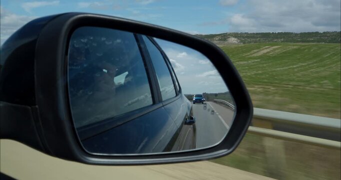 Rearview mirror POV from inside a car by the road
