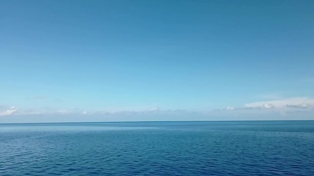 Calming deep blue ocean waves ripple under a bright clear sky in this peaceful cinematic nature video clip