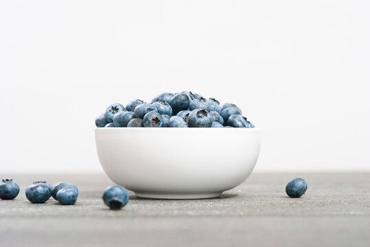 bilberry fruits at china bowl, on dark wood table