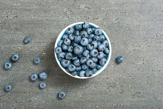 bilberry fruits at china bowl, on dark wood table