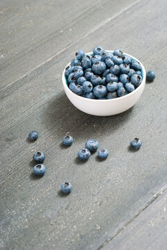 bilberry fruits at china bowl, on dark wood table
