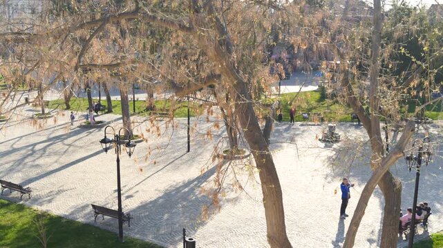 Panoramic view of the city of Nis' new park with a pavement and tourists on a sunny day