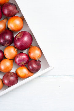 onions on white wood tray, wooden table background