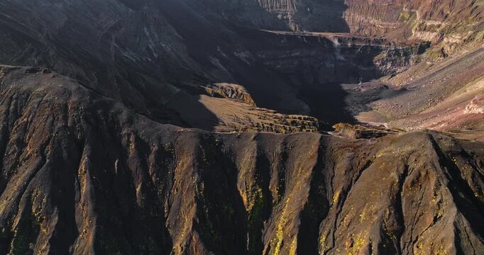 Ambrym Island's volcanic peaks and a deep caldera are viewed from an aerial perspective, showing the rugged, dark landscape and geological features of the active volcano. Drone flight panorama