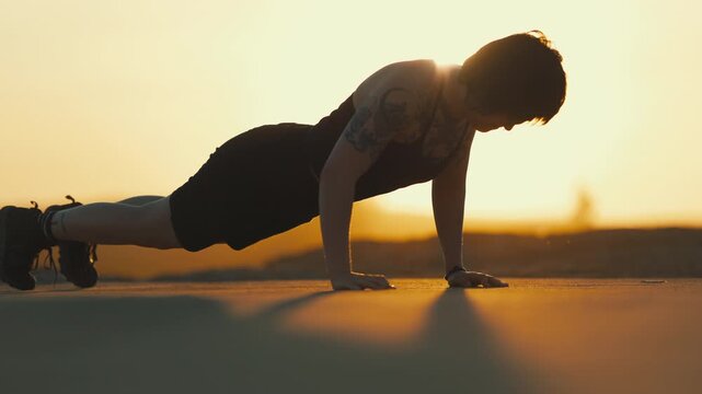 Athletic woman doing push ups at sunset