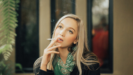 Stylish Woman Relaxing with Cigarette and Indoor Plant - Dark Jacket and Green Scarf Detail Photography Stock Image. © AU USAnakul