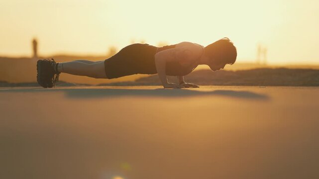 Athletic man doing push ups outdoor at sunset