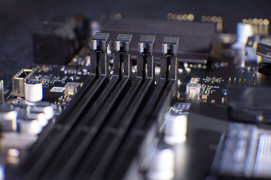 Close view of a motherboard with slots for memory modules and electronic components located on a dark background