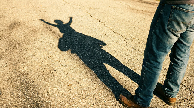 Long shadow of a child sitting on father's shoulders during a sunny walk