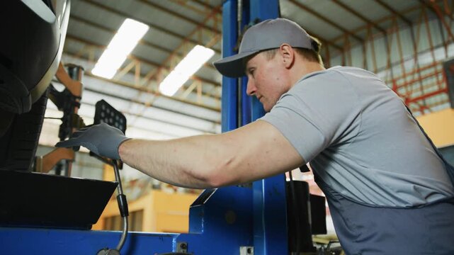 Focused professional auto mechanic adjusting car lift for undercarriage inspection in garage