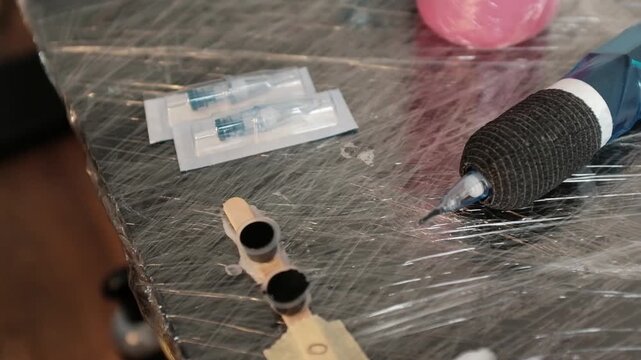 Close-up of a female tattoo artist in black latex gloves gets her working stuff ready. Preparing the needles for work. Opening new sterile needles from the box.