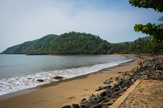 Scenic beach with gentle waves and lush green hills along the coastline in Gokarna, Karnataka