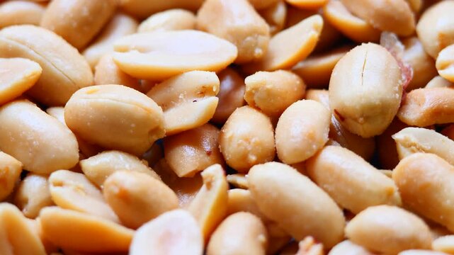 Close-up rotating peanuts with visible salt crystals and roasted surface, perfect for healthy snack concepts, product promotion and food industry visuals
