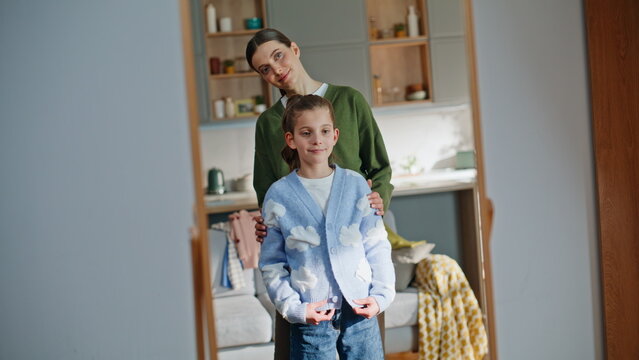 Daughter admiring new outfit with mom in mirror closeup. Girl looking reflection