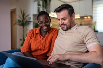 Obraz premium Couple sharing joyful moments while working on a laptop in a cozy living room setting