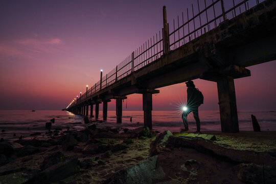 Dramatic moning sky over a rocky beach with a traveler.