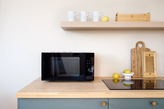 Modern kitchen interior with microwave, induction hob and decor