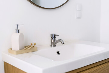 Fototapeta premium White bathroom sink with bamboo toothbrushes and soap dispenser