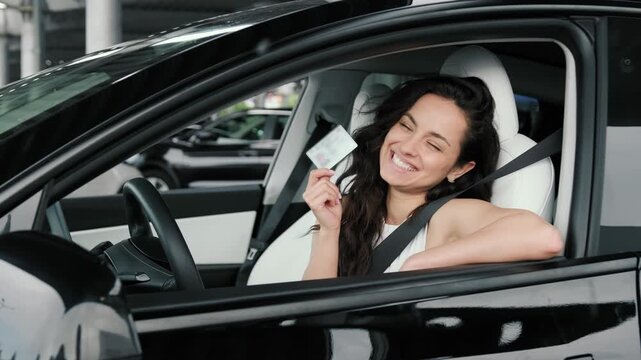 Happy lady holding license and sitting in the car. Slow motion