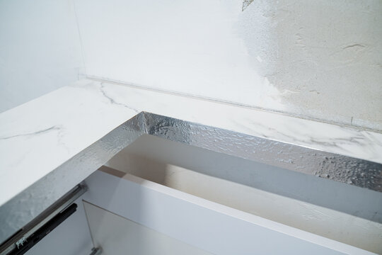 Countertop Edge Finishing. Marble Edge With Sealing Tape. Installer Treats Marble Corner With Insulation Tape. Closeup Of Marble Countertop Edge With Seam And Sealing Materials