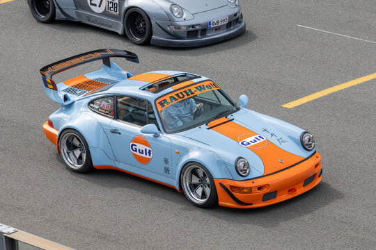Stavelot, Belgium - April 5th 2026 : View on a blue and orange Porsche 964 Rauh-Welt Begriff driving on a street.
