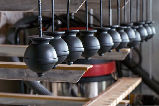 Matte black round furniture parts hanging for drying after spray coating inside industrial curing chamber suspended on metal rails with uniform spacing workshop