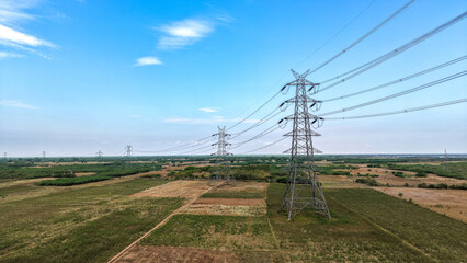 High voltage transmission towers across rural landscape with power lines aerial view © VisualTreat12