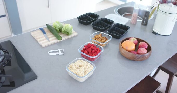Camera is panning and zooming across kitchen island, revealing prep trays, sink and stools
