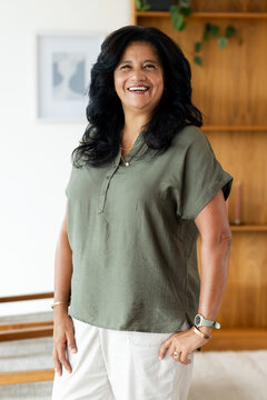 Mature African woman smiling in living room, wearing olive blouse and wristwatch with green band