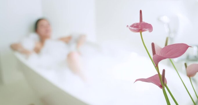 Camera pulling focus revealing woman reclining in tub, arm draping rim, foam covering, seeking calm