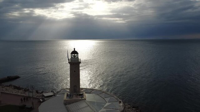 Aerial shot of a traditional stone lighthouse on a pier at the coastline